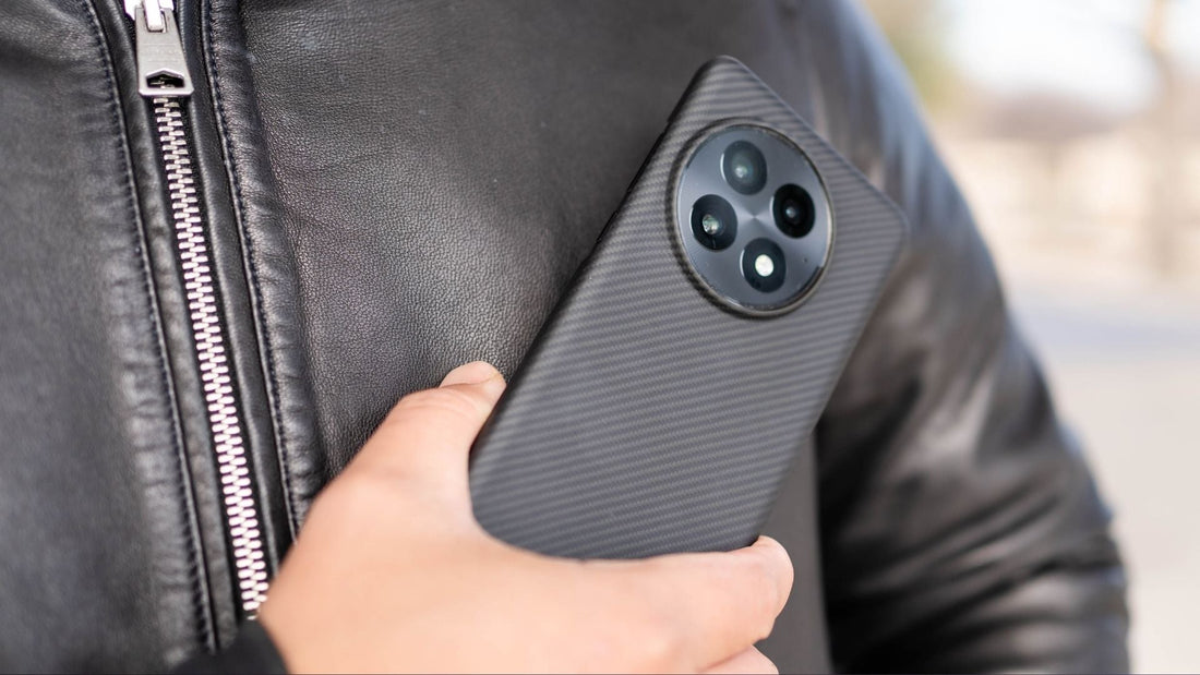 man in leather jacket holding a oneplus 13 with fiberborne case