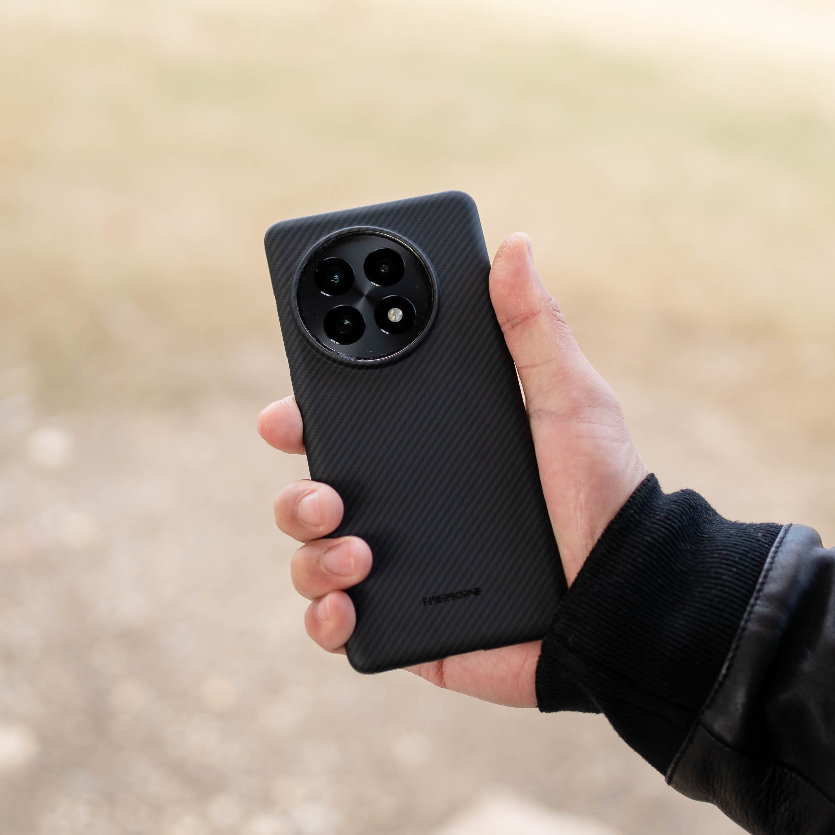 Close-up of a person holding a black OnePlus 13 phone case with a distinctive circular camera cutout.